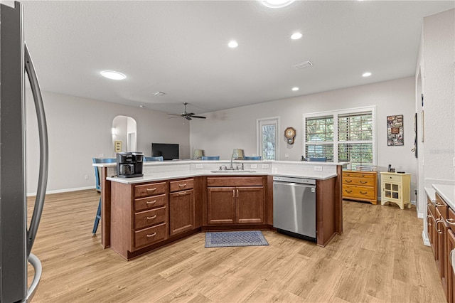 kitchen featuring light wood-type flooring, a kitchen island with sink, sink, stainless steel appliances, and ceiling fan