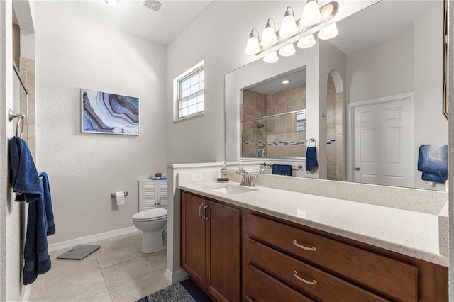 bathroom featuring a tile shower, vanity, toilet, and tile patterned floors