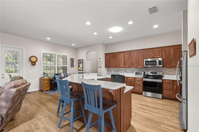 kitchen featuring light hardwood / wood-style floors, tasteful backsplash, sink, a breakfast bar area, and appliances with stainless steel finishes