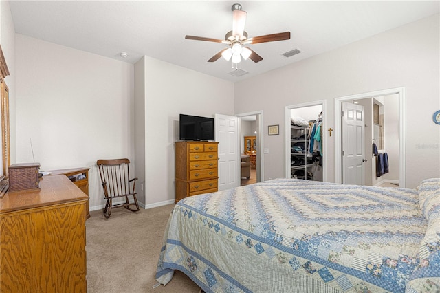 bedroom with a spacious closet, a closet, ceiling fan, and light carpet