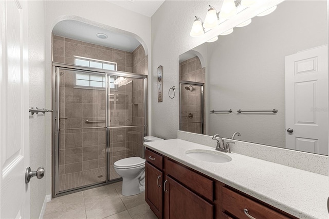 bathroom featuring tile patterned flooring, vanity, toilet, and an enclosed shower