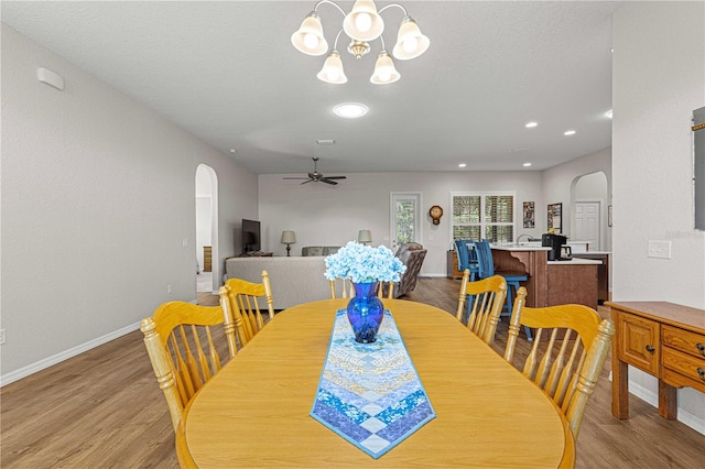 dining area with light hardwood / wood-style flooring and ceiling fan with notable chandelier