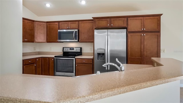 kitchen featuring stainless steel appliances, vaulted ceiling, and kitchen peninsula