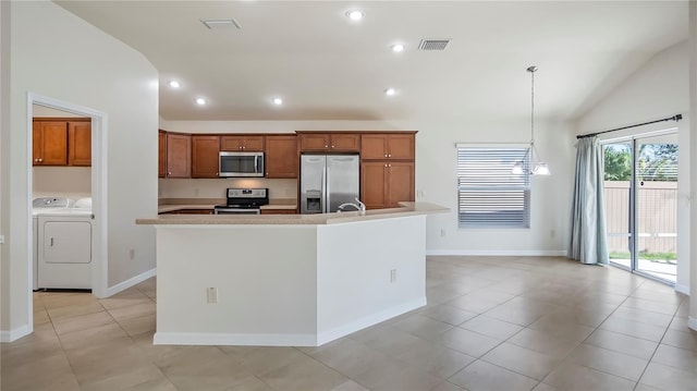 kitchen with pendant lighting, washer and dryer, an island with sink, lofted ceiling, and appliances with stainless steel finishes