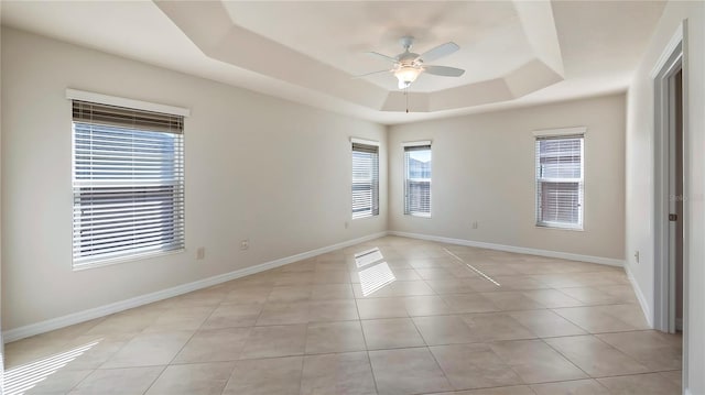 unfurnished room featuring light tile patterned floors, a tray ceiling, and ceiling fan