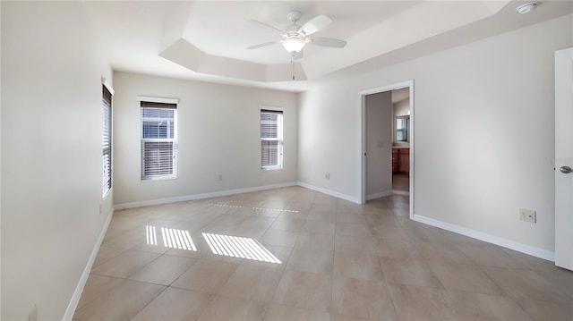 spare room with a tray ceiling and ceiling fan