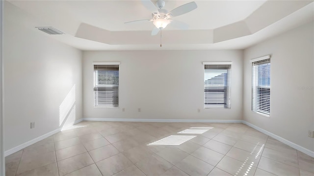 tiled spare room with a raised ceiling and ceiling fan