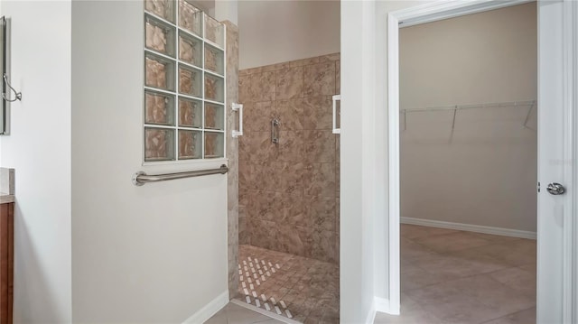 bathroom with a tile shower, tile patterned flooring, and vanity