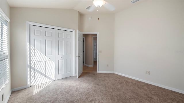 unfurnished bedroom featuring lofted ceiling, ceiling fan, light colored carpet, and a closet