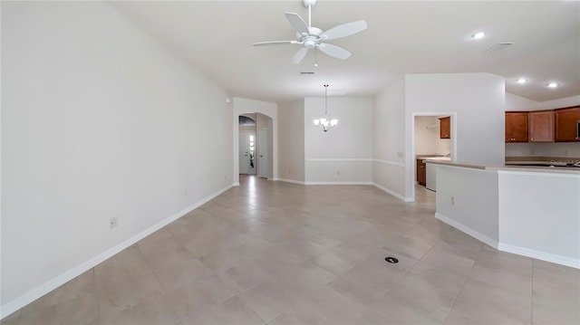 unfurnished living room with ceiling fan with notable chandelier and vaulted ceiling