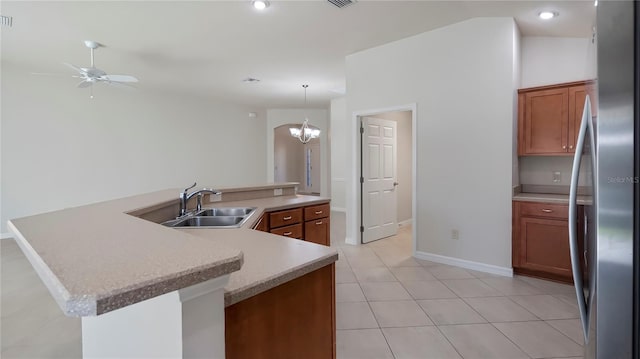 kitchen featuring sink, ceiling fan with notable chandelier, lofted ceiling, stainless steel refrigerator, and decorative light fixtures