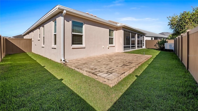 back of property with a sunroom, a patio area, and a yard