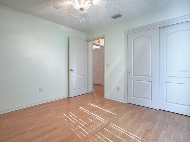 unfurnished bedroom featuring ceiling fan, a closet, a textured ceiling, and light wood-type flooring