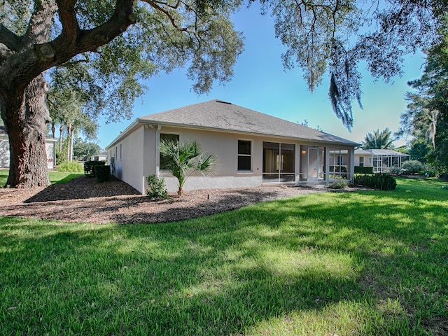 rear view of property featuring a lawn and a sunroom