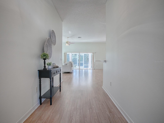 hall featuring a textured ceiling and light wood-type flooring