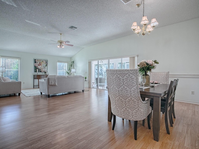 dining room with a textured ceiling, ceiling fan with notable chandelier, light hardwood / wood-style floors, and lofted ceiling