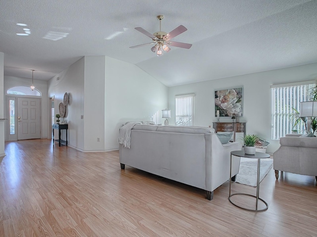 living room featuring ceiling fan, plenty of natural light, lofted ceiling, and light wood-type flooring