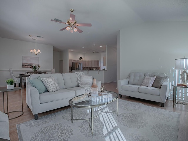 living room with ceiling fan with notable chandelier and light wood-type flooring