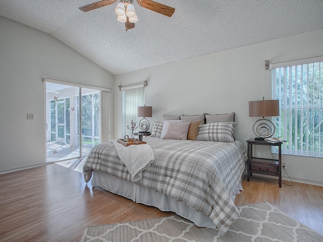 bedroom featuring light wood-type flooring, a textured ceiling, access to outside, vaulted ceiling, and ceiling fan