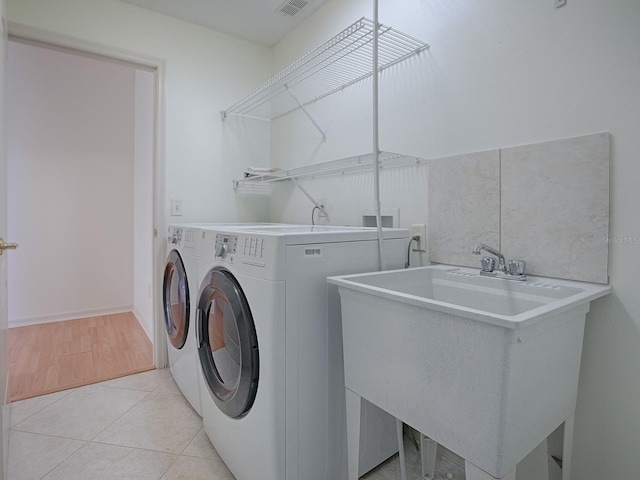 laundry room featuring light tile patterned floors, sink, and washing machine and clothes dryer