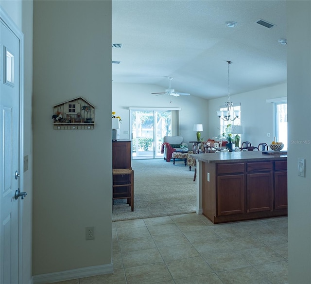 kitchen with light carpet, pendant lighting, and ceiling fan with notable chandelier