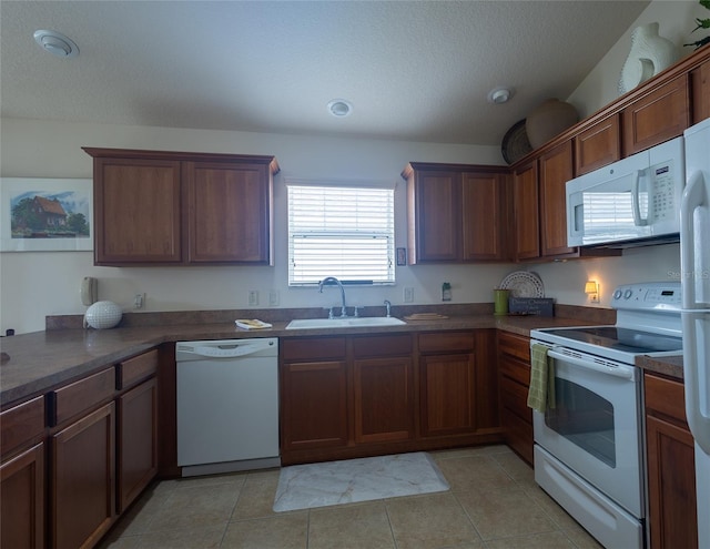 kitchen featuring sink, a textured ceiling, white appliances, and light tile patterned floors