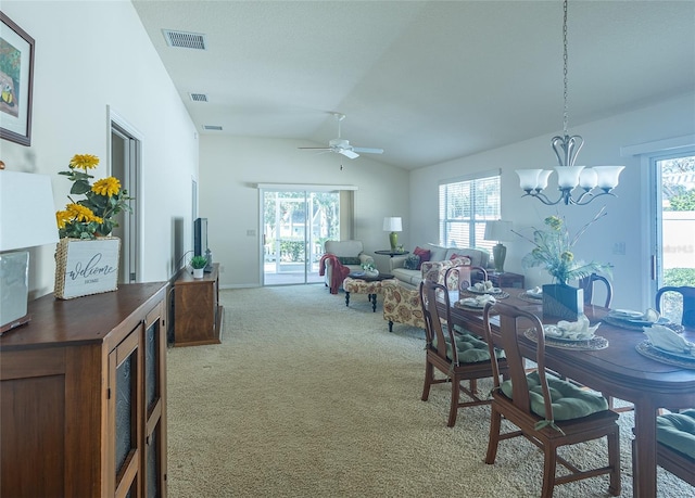 carpeted dining area with lofted ceiling, ceiling fan with notable chandelier, and a healthy amount of sunlight