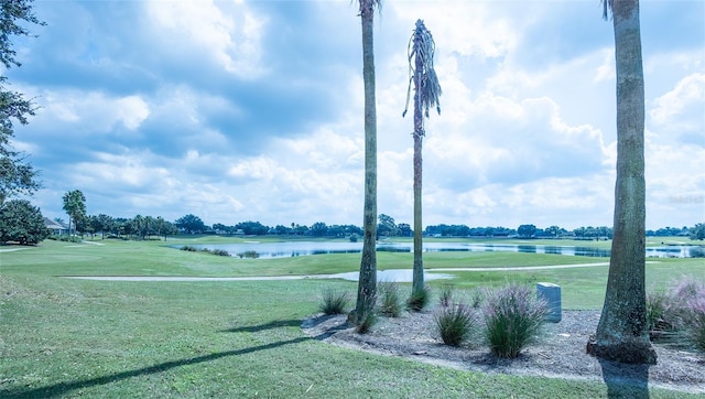 surrounding community with a water view and a lawn