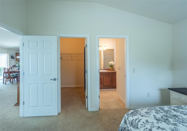 bedroom with a spacious closet, vaulted ceiling, light carpet, and a closet