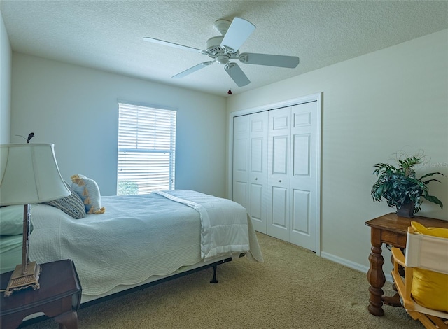 carpeted bedroom featuring a closet, a textured ceiling, and ceiling fan