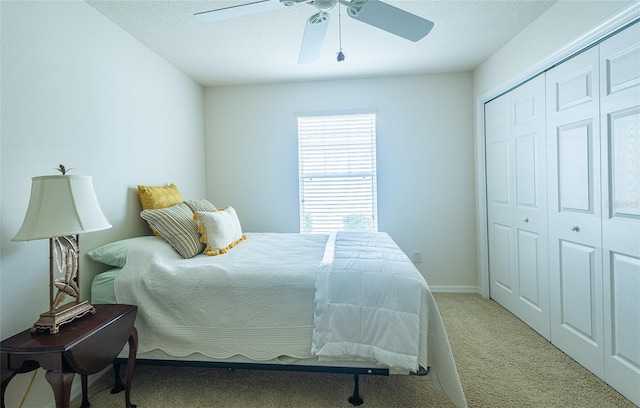 bedroom featuring a closet, ceiling fan, a textured ceiling, and light colored carpet