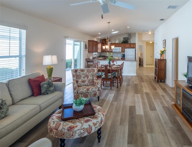 living room with lofted ceiling, sink, ceiling fan with notable chandelier, and light hardwood / wood-style floors