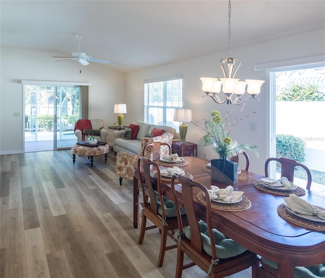 dining area with vaulted ceiling, ceiling fan with notable chandelier, and light hardwood / wood-style flooring