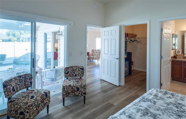 bedroom with ensuite bathroom, a walk in closet, a closet, and light hardwood / wood-style flooring