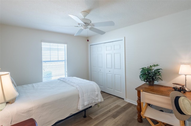 bedroom featuring ceiling fan, light hardwood / wood-style flooring, a closet, and a textured ceiling