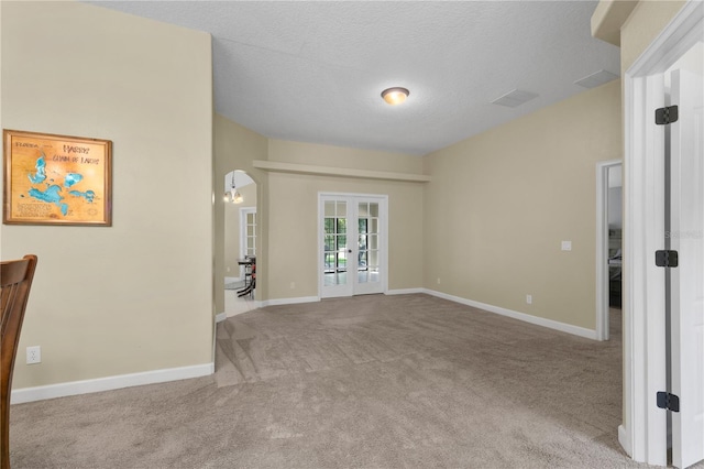 carpeted spare room with french doors and a textured ceiling