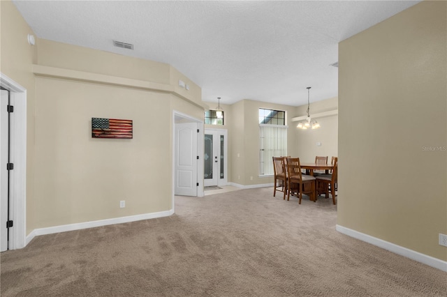 interior space with carpet flooring, a textured ceiling, and a chandelier