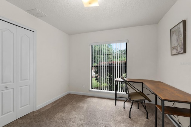 home office featuring a textured ceiling, carpet floors, and plenty of natural light