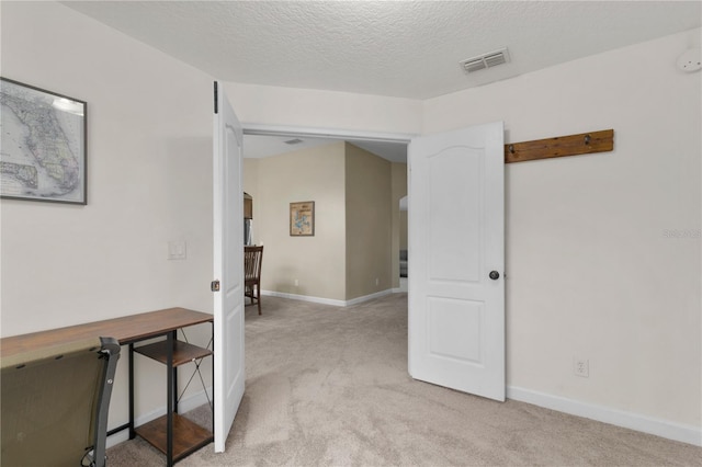 interior space featuring light colored carpet and a textured ceiling