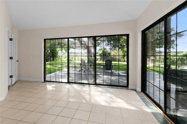 tiled empty room featuring vaulted ceiling