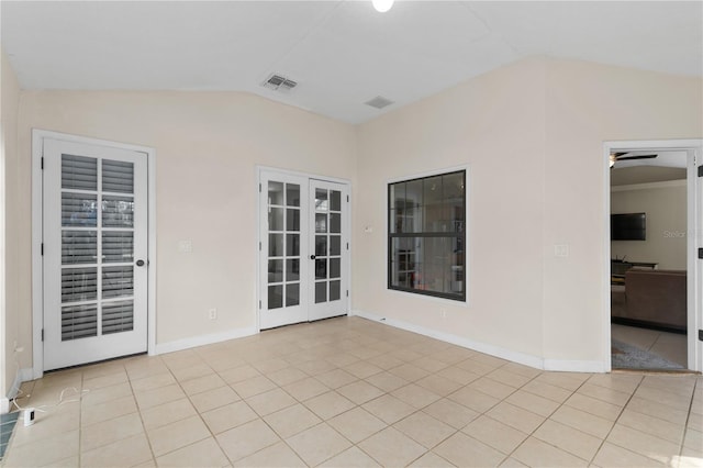 tiled spare room featuring ceiling fan, vaulted ceiling, and french doors