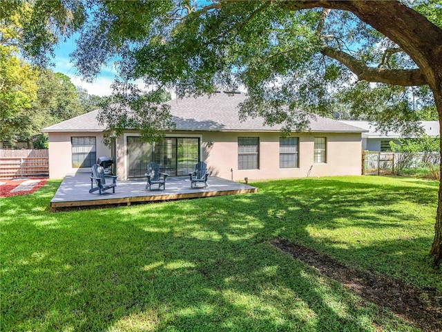 rear view of house featuring a deck and a lawn