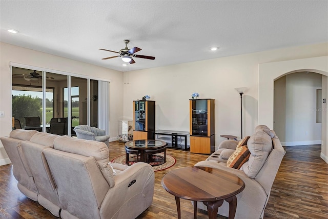 living room featuring ceiling fan, a textured ceiling, and dark hardwood / wood-style flooring