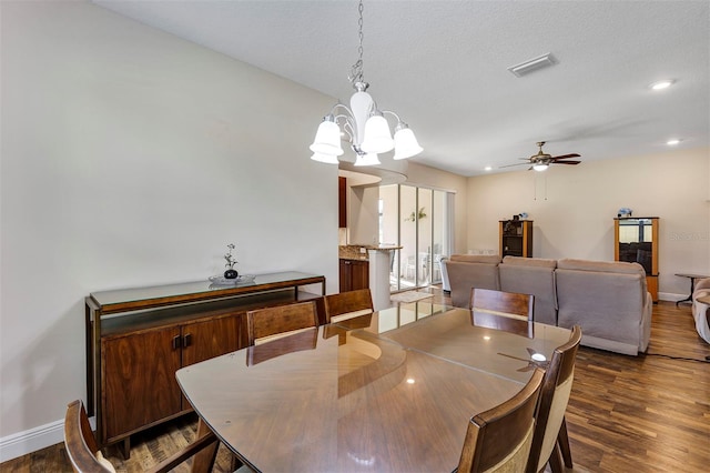 dining area featuring a textured ceiling, ceiling fan with notable chandelier, and dark hardwood / wood-style floors