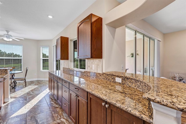 kitchen featuring ceiling fan, light stone counters, and tasteful backsplash