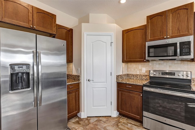 kitchen featuring a textured ceiling, backsplash, stone counters, and stainless steel appliances