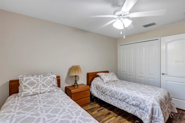 bedroom with dark wood-type flooring, ceiling fan, and a closet