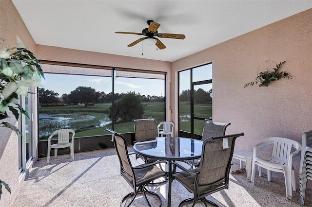 sunroom featuring ceiling fan and a water view