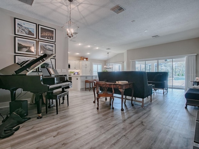 misc room with plenty of natural light, light hardwood / wood-style floors, and a chandelier