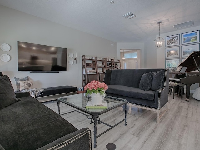 living room with light hardwood / wood-style flooring, a chandelier, and a textured ceiling